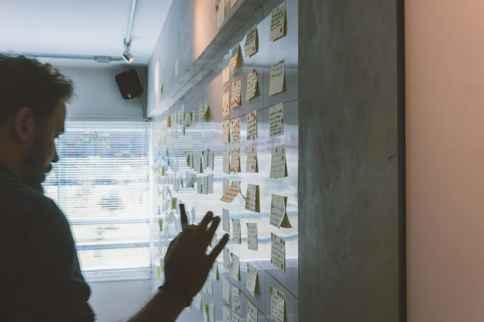 Mann ordnet handschriftliche Notizen an einer Glaswand